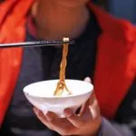 Eating a bowl of noodles with chopsticks